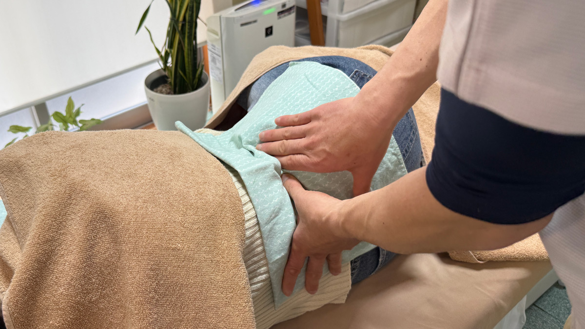 八王子市大塚で身体の状態を確認しながら腰のマッサージ施術を行っている様子